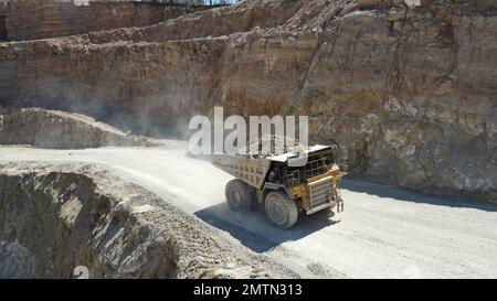 Großer Steinbruch-Müllwagen voller Steine. Ich transportiere das Erz in den Zerkleinerer. Bergbaumaschinen, die das Material für die Produktion transportieren. Stockfoto