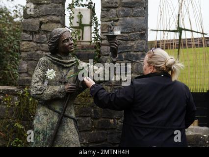 Eine Frau hat einen traditionellen St. Brigid's Cross, das aus Steigungen bis zu einer Statue von St. Brigid in St. Brigids heiligem Brunnen in Co Kildare. Am 1. Februar findet der St. Brigid's Day statt, der von vielen in Irland als erster Frühlingstag angesehen wird. Bilddatum: Mittwoch, 1. Februar 2023. Stockfoto