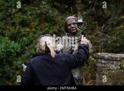 Eine Frau hat einen traditionellen St. Brigid's Cross, das aus Steigungen bis zu einer Statue von St. Brigid in St. Brigids heiligem Brunnen in Co Kildare. Am 1. Februar findet der St. Brigid's Day statt, der von vielen in Irland als erster Frühlingstag angesehen wird. Bilddatum: Mittwoch, 1. Februar 2023. Stockfoto