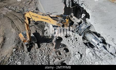 Hydraulikbagger mit Hydraulikhammer zum Abriss eines Industriegebäudes. Stockfoto