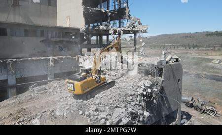 Hydraulikbagger mit Hydraulikhammer zum Abriss eines Industriegebäudes. Stockfoto