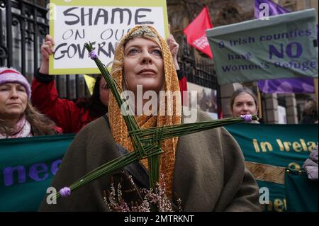 Lisamarie Johnson (Zentrum), mit einer traditionellen St. Brigid's Cross Made from Rushes, nimmt an einer Rallye zum St. Brigid's Day vor Leinster House, Dublin Teil und fordert die Regierung auf, Maßnahmen gegen Gewalt gegen Frauen in Irland zu ergreifen. Die Kundgebung fand zeitgleich mit dem St. Brigid's Day statt, wobei Redner forderten, dass Frauen im Geiste der keltischen Göttin und der Christlichen heiligen Brigid, die mit der Heilung in Verbindung gebracht werden, geschützt werden. Bilddatum: Mittwoch, 1. Februar 2023. Stockfoto