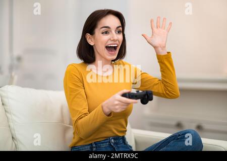 Glückliche junge Frau spielen Videospiele zu Hause Stockfoto