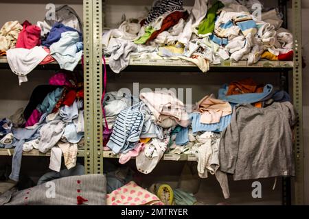 Humanitäre Hilfe Station, im Inneren des Industrielagers mit gebrauchter Kleidung für die Armen, Flüchtlinge, schutzbedürftige Menschen. Regale, Kleiderreihen Stockfoto