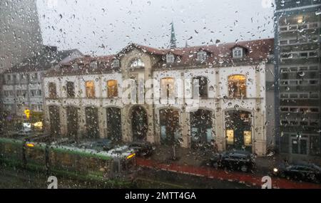 Hannover, Deutschland. 01. Februar 2023. Regentropfen laufen durch ein Fenster, eine Straßenbahn läuft im Hintergrund. Es regnet Katzen und Hunde im stürmischen Hannover. Kredit: Marco Rauch/dpa/Alamy Live News Stockfoto