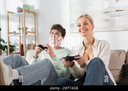 KIEW, UKRAINE - 24. OKTOBER 2022: Fröhliches junges Paar mit Joysticks beim Spielen von Videospielen Stockfoto