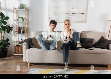 KIEW, UKRAINE - 24. OKTOBER 2022: Aufgeregtes junges Paar mit Joysticks beim Spielen von Videospielen Stockfoto