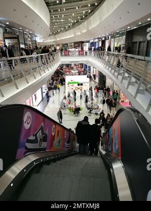Vertikales Bild einer Gegend mit Rolltreppen und Korridoren voller Menschen auf zwei Ebenen im Einkaufszentrum H2Ocio in Rivas Vaciamadrid. Stockfoto