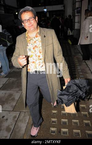 Der Fernsehmoderator Timmy Mallett aus den 80s und 90s Jahren lächelt, wenn er BBC Radio 2 verlässt. Er trägt ein ansprechendes Outfit, bestehend aus einem vielseitig gemusterten Hemd mit orangefarbenem und gelbem Blumenmuster, gestreiften Hosen und pinkfarbenen Schuhen. London, Großbritannien. 11/5/10. Stockfoto