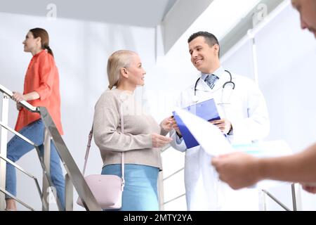 Arzt und Patient diskutieren Diagnose auf Treppen im Krankenhaus Stockfoto