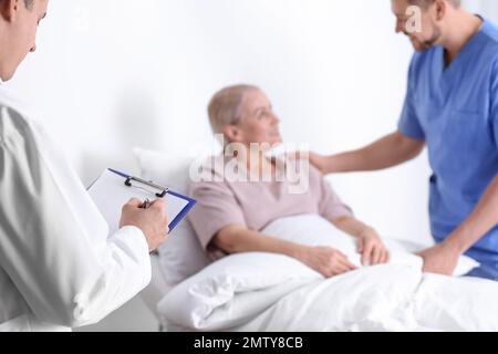 Arzt und männliche Krankenschwester Besuch Patient in der Krankenhausstation, Nahaufnahme Stockfoto