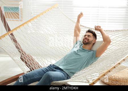 Junger Mann, der sich zu Hause in einer Hängematte entspannt Stockfoto