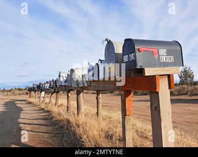 Eine lange Reihe ländlicher Briefkästen in einer isolierten, nicht zugänglichen Gemeinde in der Nähe von Bend, Oregon. Stockfoto