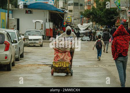 Ein palästinensischer Arbeiter schiebt einen Transportwagen mitten auf der Straße im Flüchtlingslager Jabalia während des schlechten Wetters in Gaza, 1. Februar 2023. Foto: Ramez Habboub/ABACAPRESS.COM Stockfoto