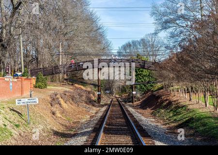 WAXHAW, NC, USA-28. JANUAR 2023: Blick auf die Bahngleise in Richtung Fußgängerbrücke, mit Pausen auf der Brücke. Grün. Stockfoto