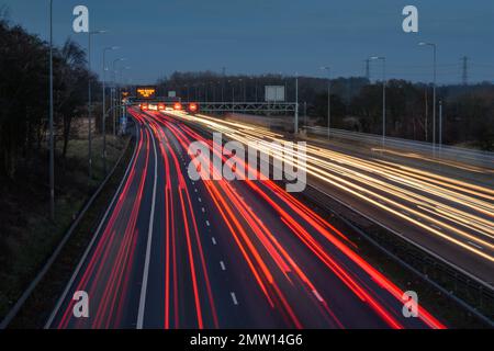 Der überhöhte Verkehr auf der Autobahn M42 während der abendlichen Hauptverkehrszeit hinterlässt aufgrund der langsamen Verschlusszeit und langen Belichtungszeiten helle Spuren und Streifen. Stockfoto