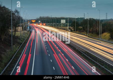 Der überhöhte Verkehr auf der Autobahn M42 während der abendlichen Hauptverkehrszeit hinterlässt aufgrund der langsamen Verschlusszeit und langen Belichtungszeiten helle Spuren und Streifen. Stockfoto