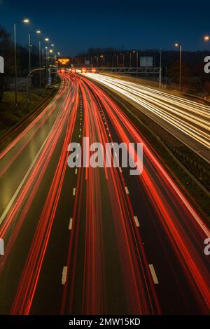 Der überhöhte Verkehr auf der Autobahn M42 während der abendlichen Hauptverkehrszeit hinterlässt aufgrund der langsamen Verschlusszeit und langen Belichtungszeiten helle Spuren und Streifen. Stockfoto