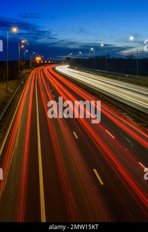 Der überhöhte Verkehr auf der Autobahn M42 während der abendlichen Hauptverkehrszeit hinterlässt aufgrund der langsamen Verschlusszeit und langen Belichtungszeiten helle Spuren und Streifen. Stockfoto