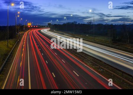 Der überhöhte Verkehr auf der Autobahn M42 während der abendlichen Hauptverkehrszeit hinterlässt aufgrund der langsamen Verschlusszeit und langen Belichtungszeiten helle Spuren und Streifen. Stockfoto