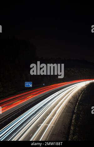 Leichte Pfade, die der schnelle Verkehr durch die Nacht auf der Autobahn M40 in Großbritannien führte. Langsame Verschlusszeit und Fotos mit langer Belichtung. Stockfoto