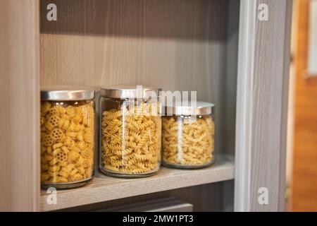 Verschiedene ungekochte Cerealien, Getreide, Bohnen und Nudeln für gesundes Kochen in Glasgefäßen. Sauberes Essen, veganes, ausgewogenes Ernährungs-Konzept Stockfoto