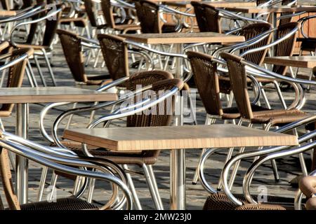 Die Holztische mit Metallsockeln, Stühle mit Korbrückenstützen und Metallarmlehnen und -Beine im Freien Stockfoto