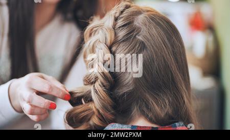 Die Make-up-Künstlerin macht einen Zopf für das Model. Stockfoto