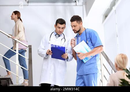 Arzte, die auf Treppen im Krankenhaus über die Patientendiagnose diskutieren Stockfoto