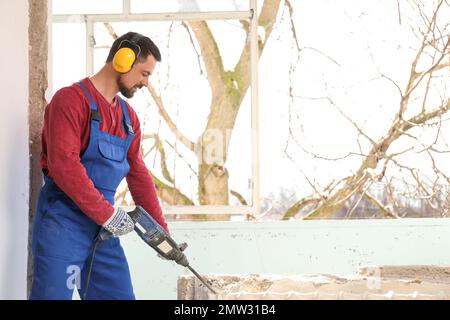 Arbeiter mit Bohrhammer für Fenstermontage im Innenbereich Stockfoto