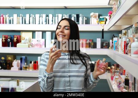 Junge Frau mit Parfümflaschen im Laden Stockfoto