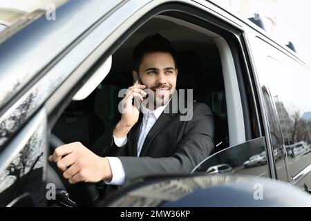 Attraktiver junger Mann, der während der Fahrt mit dem Smartphone spricht Stockfoto