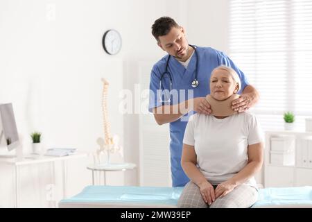 Orthopädin, der das Halsband am Hals des Patienten in der Klinik anlegt Stockfoto