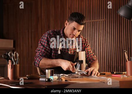 Ein Mann, der in der Werkstatt Leder mit einer Schere schneidet Stockfoto