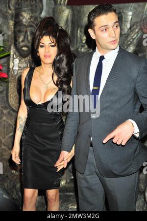 Amy Winehouse trägt ein kleines schwarzes Kleid und hält sich fest an ihren neuen Freund Reg Traviss, um das neue Camden Restaurant Shaka Zulu zu eröffnen. Nach London. UK. 8/4/10. . Stockfoto