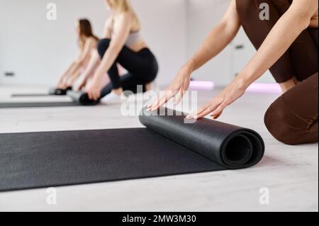 Faltmatten für weibliche Fitnessgruppen beendeten Yoga-Session im Sportverein Stockfoto