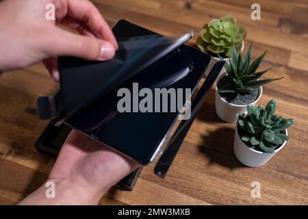 Samsung Galaxy Z Fold 4 in grau-grüner Farbe. Ein Mann packt das neue Handy aus. Stockfoto