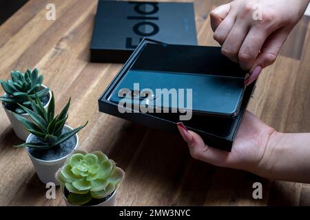 Samsung Galaxy Z Fold 4 in grau-grüner Farbe. Eine Frau packt das neue Handy aus. Stockfoto