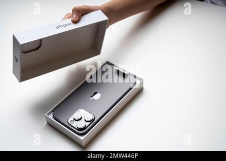 Ein Mädchen hat das neueste iPhone 14 Pro max, Space Black. Apfels neuestes Handy war mit drei Kameras ausgestattet. Weißer Hintergrund. Stockfoto
