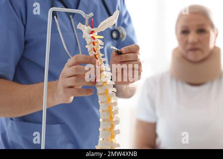 Männlicher Orthopäde erklärt dem Patienten die Struktur der Wirbelsäule, Nahaufnahme Stockfoto