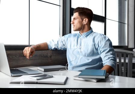 Ein Mann, der am Tisch im Café Hörbücher hört Stockfoto