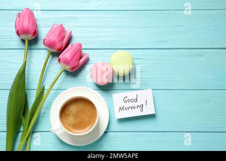 Flache Liegezusammensetzung mit Nachricht „GUTEN MORGEN“ und Kaffee auf hellblauem Holztisch. Platz für Text Stockfoto