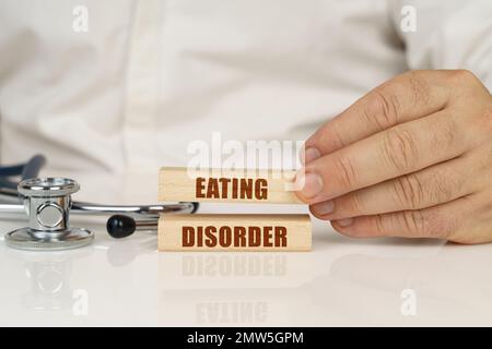 Medizinisches Konzept. Auf einer weißen Oberfläche, einem Stethoskop und Holzplatten mit der Inschrift - Essstörung Stockfoto