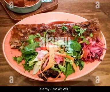 Blick von oben auf argentinisches Schweinerippchen mit farbenfrohem Salat auf einem Teller Stockfoto