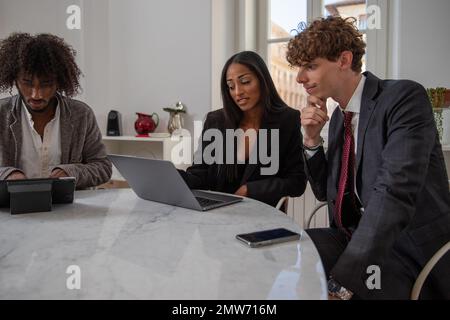 Eine multiethnische Gruppe von drei Geschäftsleuten, die technische Geräte verwenden Stockfoto