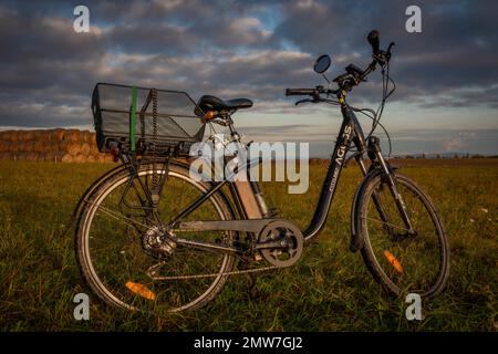 Heubälle und Elektrofahrrad auf dem Feld bei Ceske Budejovice Stadt in Sonnenaufgang Zeit in Farbe Herbst Stockfoto