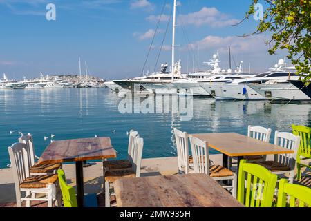 Ein Straßencafe-Tisch entlang der Promenade des Jachthafens Flisvos und Promenade in der Küstenstadt Palaio Faliro, Griechenland, mit Blick auf Piräus Stockfoto