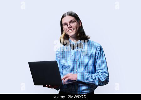 Ein schlauer Student, der ein Notebook benutzt und in die Kamera schaut, weißer Hintergrund Stockfoto