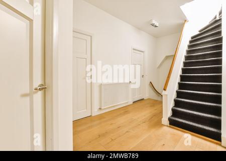 Ein leerer Raum mit weißen Wänden und Holzfußboden auf der rechten Seite, es gibt eine Treppe, die zur zweiten führt Stockfoto