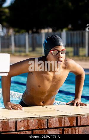 Ein vertikaler Schuss eines Schwimmerjungen im Außenpool mit Schwimmbrille und einer Kappe, vertikaler Schuss Stockfoto